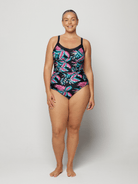 Woman wearing a tropical leaf patterned swimsuit on a plain background