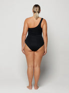 Person wearing a black swimsuit on a plain background