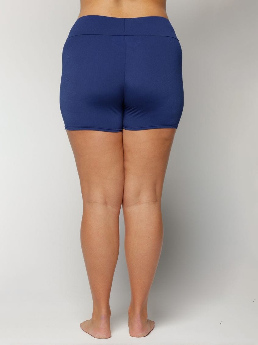 Person wearing chlorine resistant blue shorts on a plain background