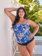 Brunette model wears flattering blue floral flouncy bandeau tankini top with straps that can be removed