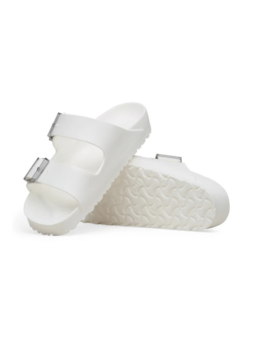 A pair of white double-strap slide sandals with textured soles and small silver buckle details, shown on a clean white background.