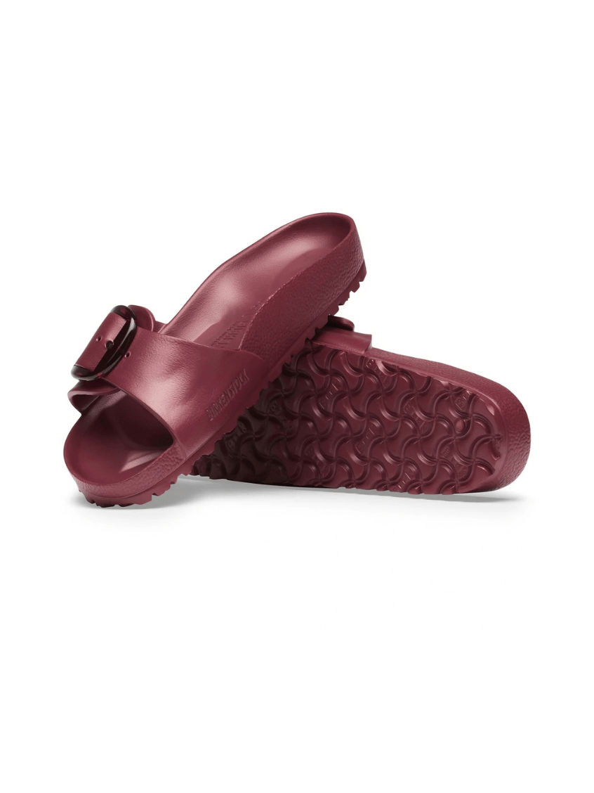 A pair of burgundy molded slide sandals with a single strap and a buckle closure, shown on a clean white background.