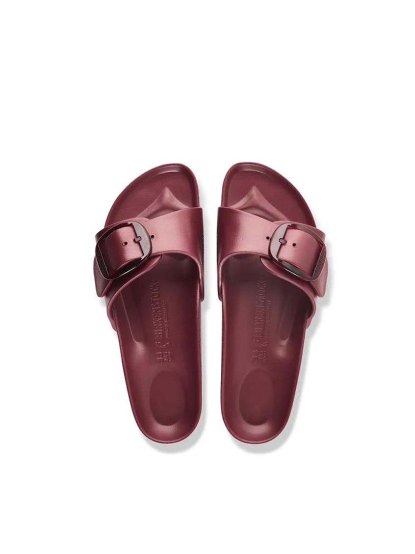 A pair of metallic burgundy slide sandals with double straps and silver-tone buckle details, shown from a top-down view on a white background.