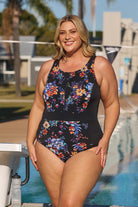 Model wearing black floral zip up swimsuit at pool