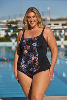 Blonde model wearing black blue and orange floral one piece at pool
