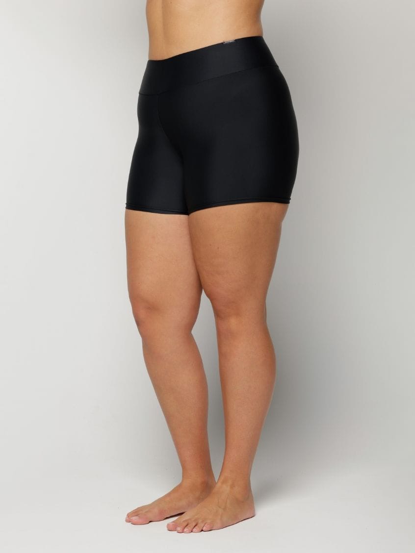 Woman wearing black high-waisted shorts on a plain background