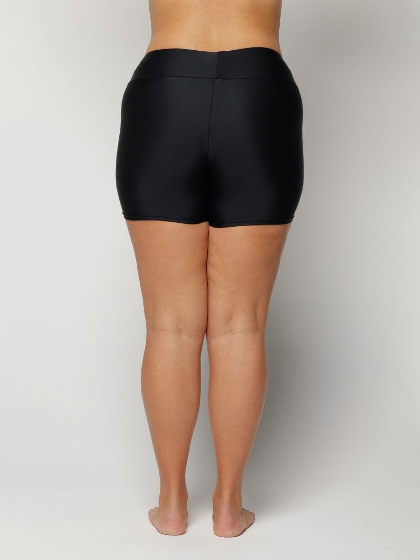 Woman wearing black shorts on a plain background