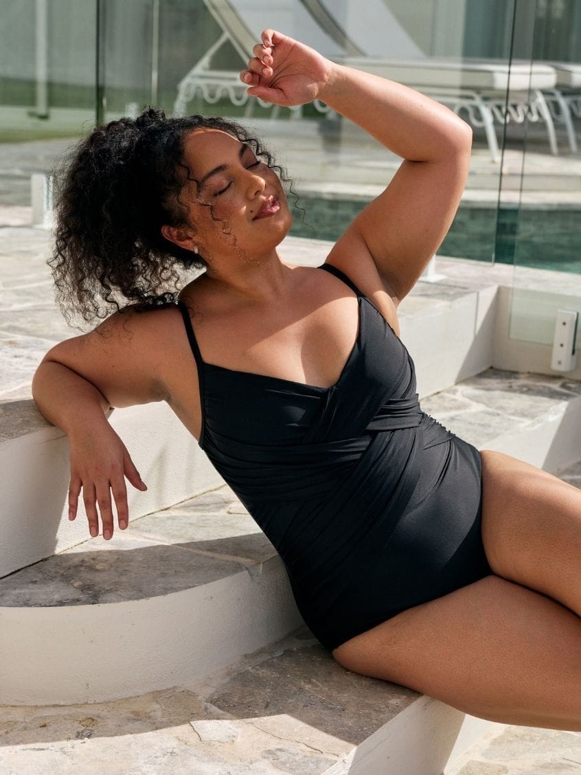 Close up detail image of model wearing a metallic black criss cross one piece in black