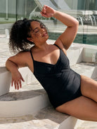 Close up detail image of model wearing a metallic black criss cross one piece in black