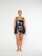Black Floral Swimdress on model standing in front of a white wall