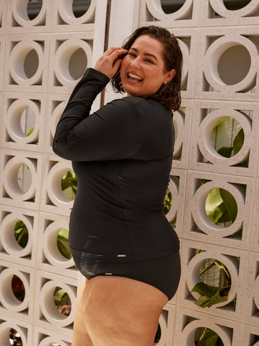 Model wearing a plain black long sleeve rash vest