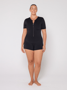 Person wearing a black zip-up jumpsuit on a white background