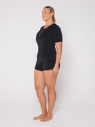 Person wearing a black boyleg swimsuit on a white background