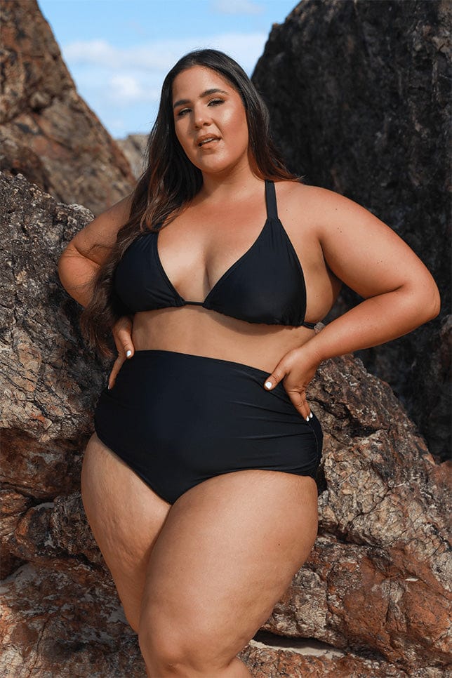 Brunette model wearing black high waisted bikini bottoms