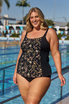 Model wearing black floral tankini top at pool
