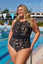 Model wearing black floral zip up one piece at pool