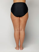 Woman wearing black high-waisted underwear on a plain background