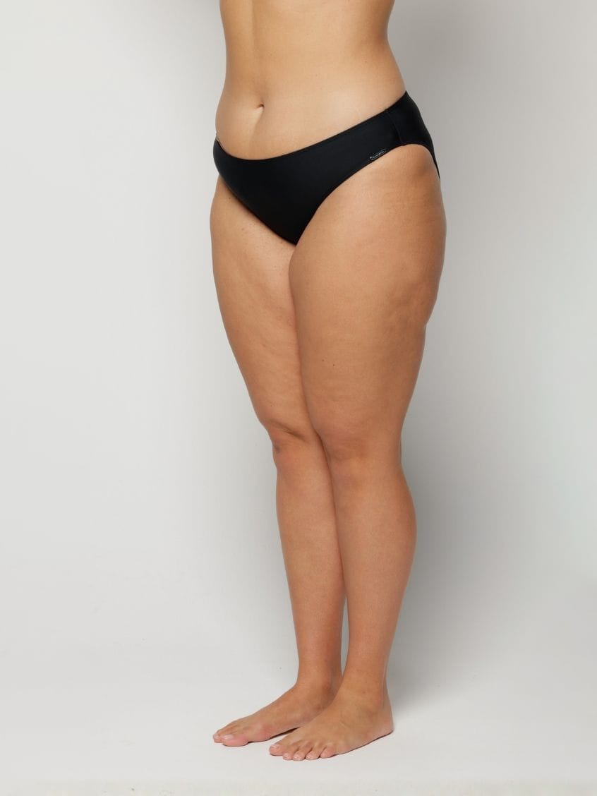 Woman wearing black underwear on a plain background