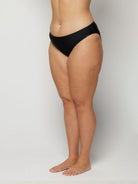 Woman wearing black underwear on a plain background