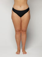 Woman wearing black underwear on a plain background