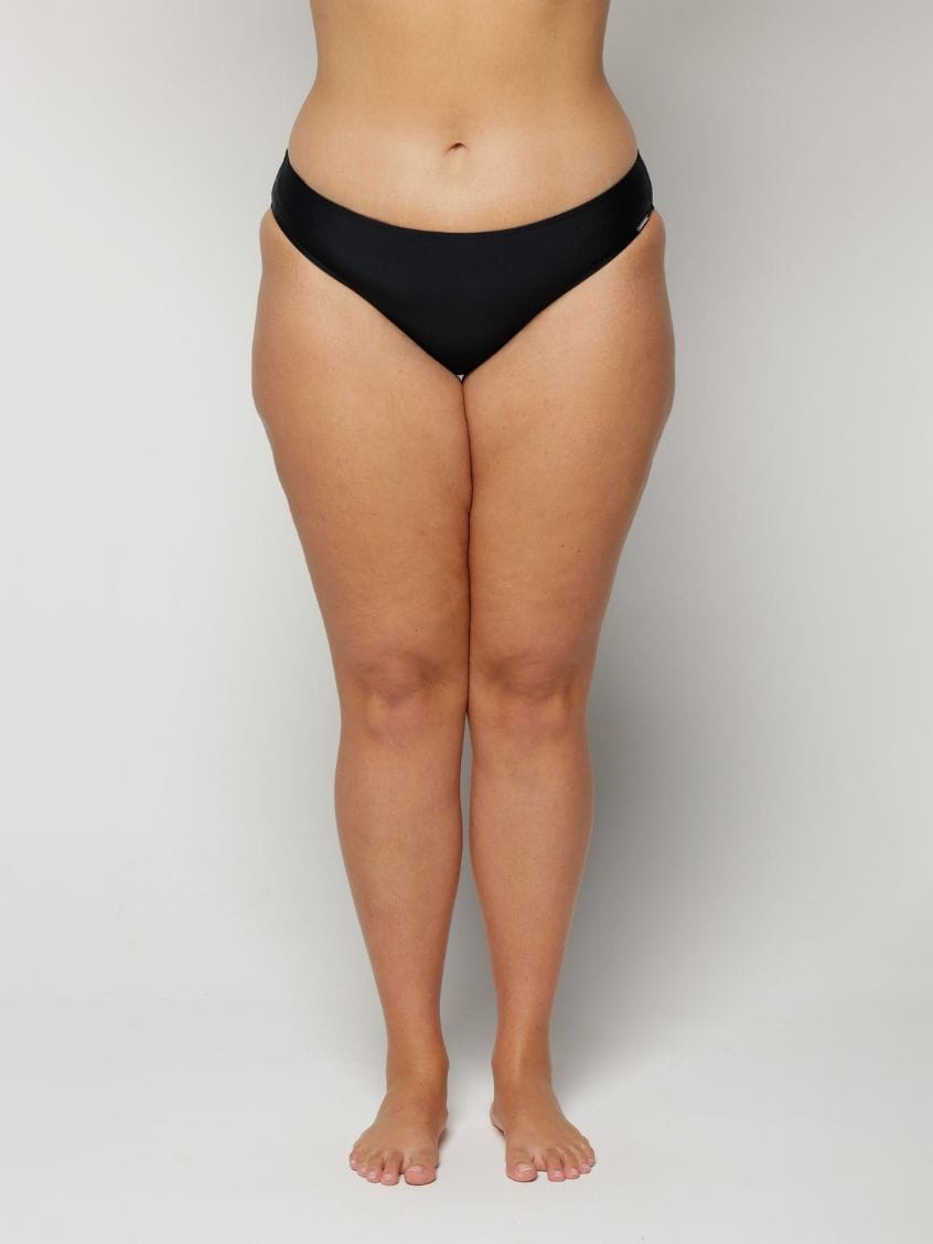 Woman wearing black underwear on a plain background