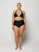 Woman wearing a black bikini on a plain background