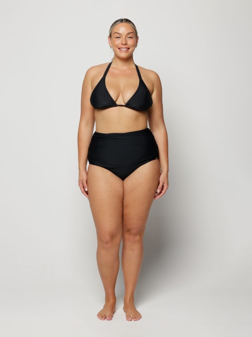 Woman wearing a black bikini on a plain background