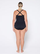 Person wearing a black swimsuit with criss-cross straps on a white background