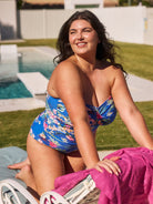 Brunette model shows flattering blue floral bandeau one piece with a shelf bra for large bust support