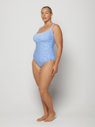 Woman wearing a light blue square neck swimsuit against a white background