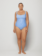 Woman wearing a blue swimsuit against a white background