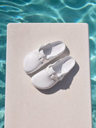 White shoes on a diving board by a pool