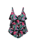 A women's 3 tier tankini swimsuit with a black background and a vibrant tropical leaf print in pink, teal, and green, featuring ruffled shoulder straps and a ruffled peplum hem.