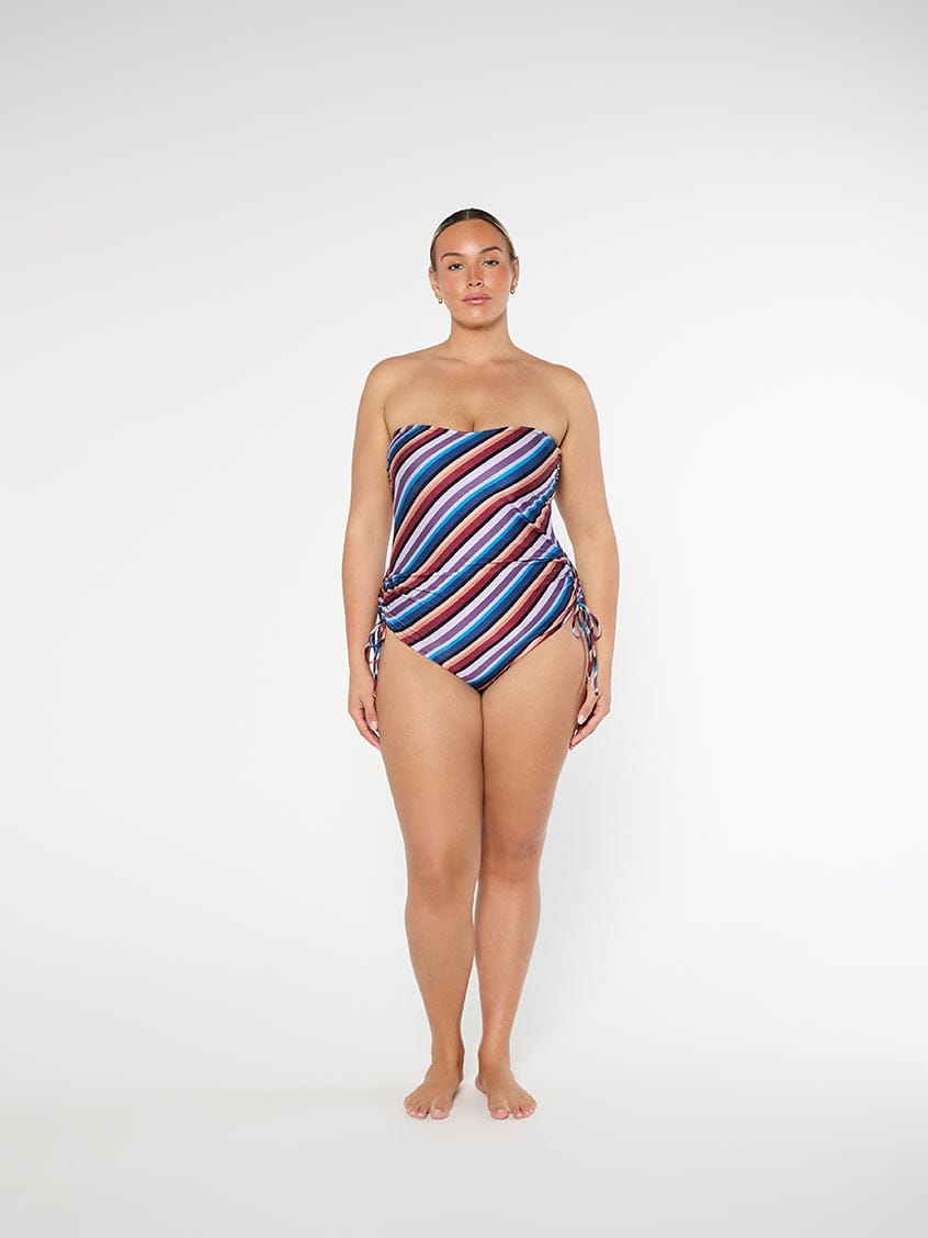 Woman wearing a strapless, multicolored striped swimsuit on a white background