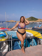 Woman in a striped bikini standing by boats on a sunny day