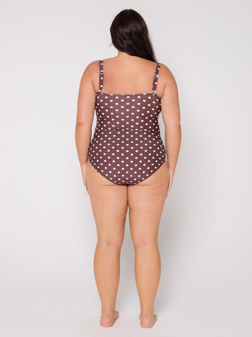 Woman wearing a polka dot swimsuit on a plain background