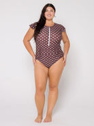 Woman wearing a brown polka dot swimsuit on a white background