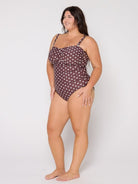 Woman wearing a brown polka dot swimsuit on a white background
