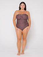 Woman wearing a strapless polka dot swimsuit on a white background