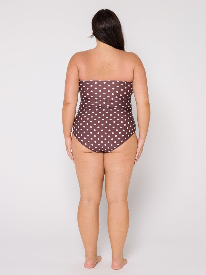 Woman wearing a strapless polka dot swimsuit on a white background