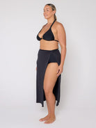 Woman wearing a black bikini with a matching skirt on a white background