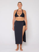 Woman wearing a black bikini and matching wrap skirt on a white background