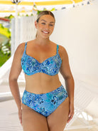 Woman wearing a blue patterned bikini set with a blurred outdoor background