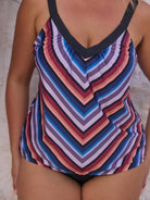 Multicolored striped swimsuit worn by a person on a neutral background