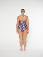 Woman wearing a strapless, multicolored striped swimsuit on a white background