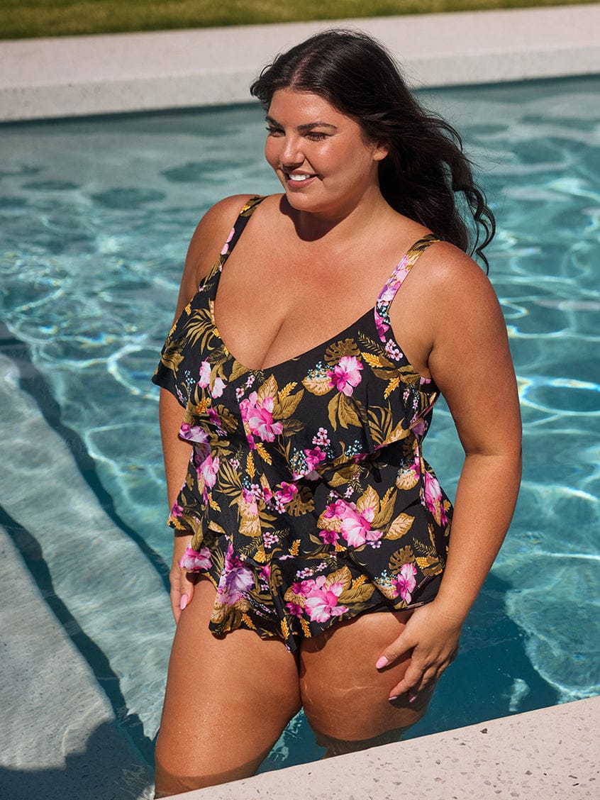 Woman in a floral swimsuit standing by a pool