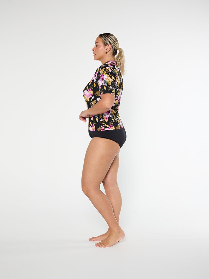 Woman wearing a floral shirt and black shorts on a white background