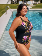 Woman wearing a black floral swimsuit by a pool