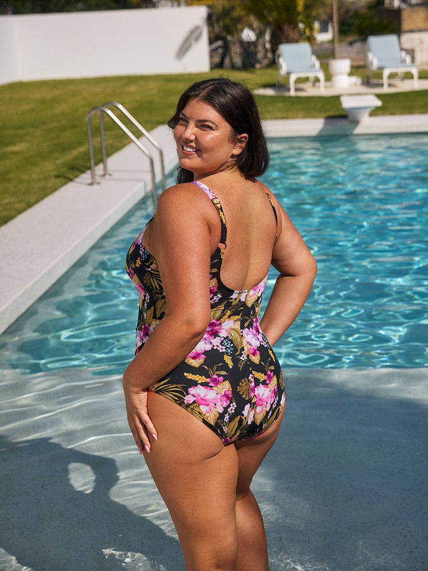 Woman in a floral swimsuit standing by a pool