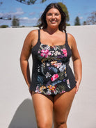 Woman wearing a black floral swimsuit against a light background